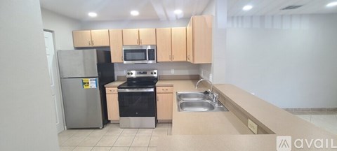 A kitchen with a refrigerator, oven, microwave, and sink.