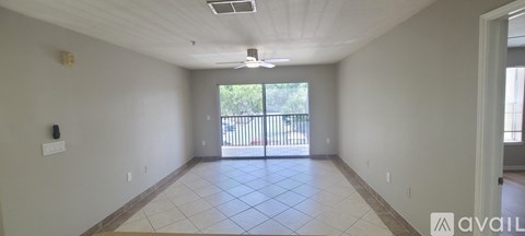 A spacious room with a sliding glass door leading to a balcony.