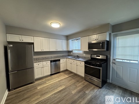A kitchen with white cabinets and a wooden floor.