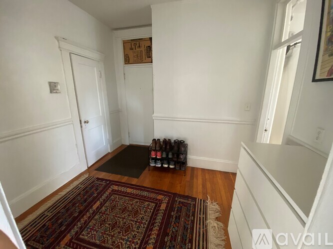 A room with a rug and a bottle of wine on the floor.