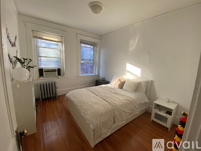 A bedroom with a bed, nightstand, and window.