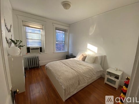 A bedroom with a bed, nightstand, and window.