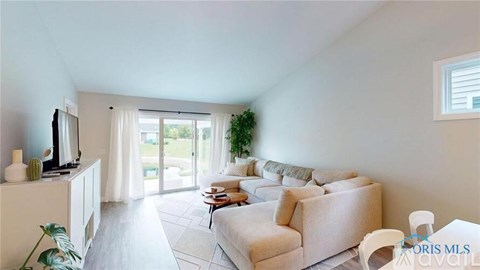A living room with a white couch and a television on a cabinet.