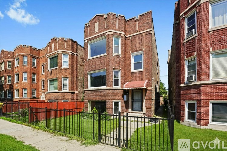 A row of red brick apartment buildings with a black fence in front.