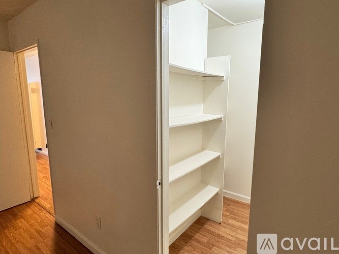 A room with a white shelving unit and wooden floors.