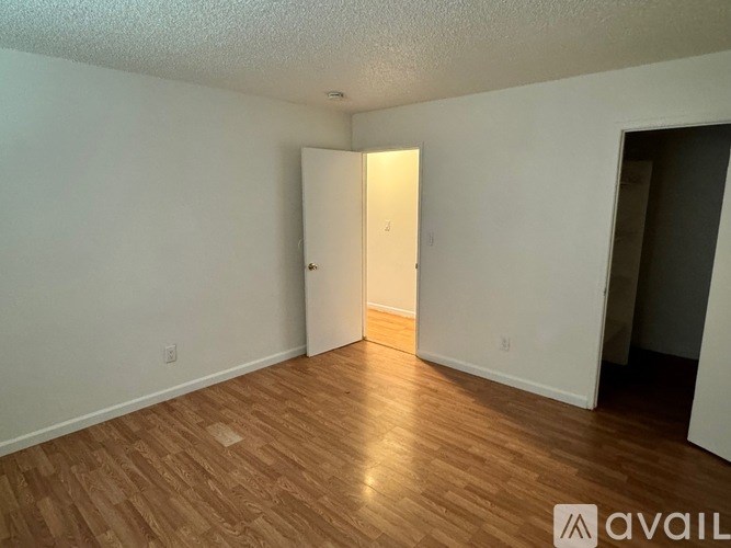 A room with wooden flooring and a door in the middle.