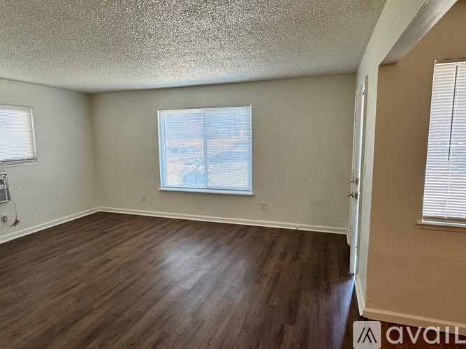 A room with wooden flooring and a window with blinds.