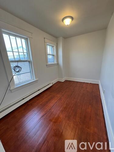 A room with wooden floors and two windows.