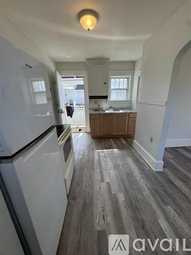 A kitchen with a white refrigerator and wooden floors.