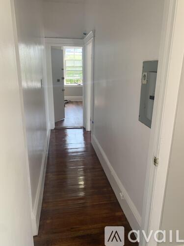 A long hallway with wood floors and white walls.