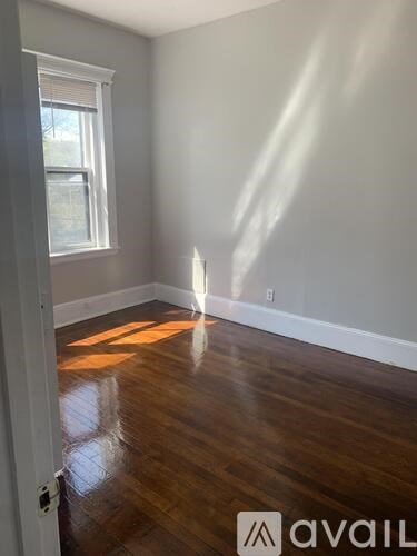 A room with wooden floors and a window letting in sunlight.
