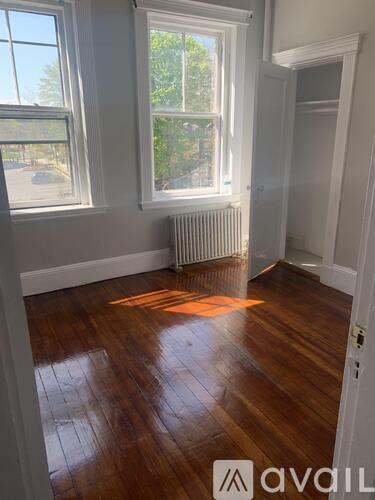 A room with wooden floors and two windows.