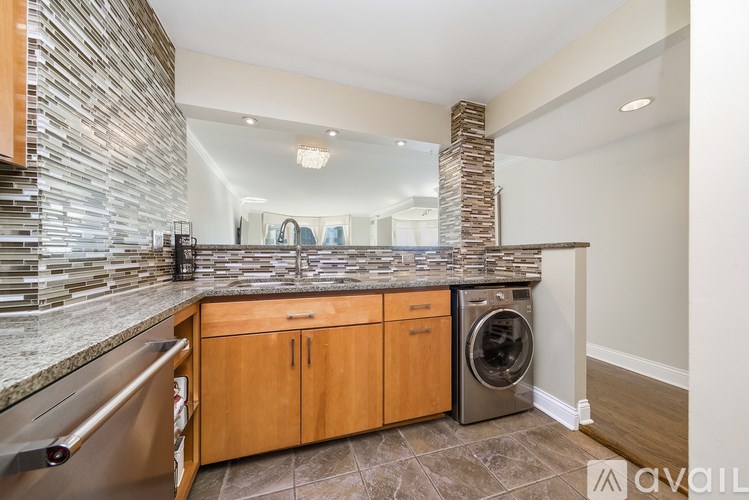 A modern kitchen with wooden cabinets and a stone backsplash.