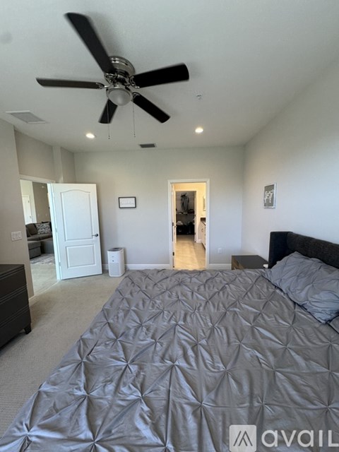 A bedroom with a large bed and a ceiling fan.