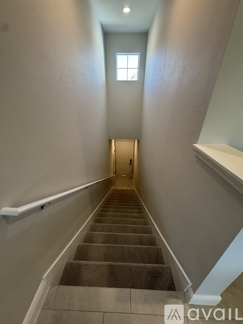 A stairway with a carpeted runner and white walls.