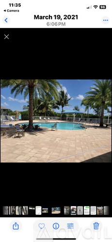 A living room with a grey couch, a desk with a chair, and a ceiling fan.
