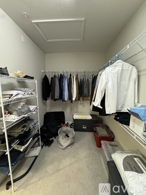 A small closet with clothes hanging and shelves with more clothes and items.