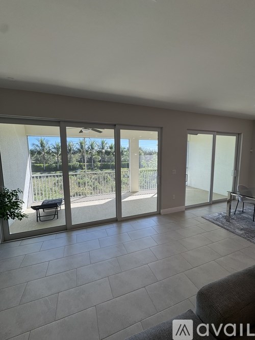 A living room with a couch and a view of a fence and trees outside.