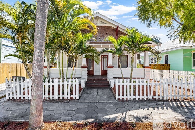 A house with a white picket fence and a tree in front.