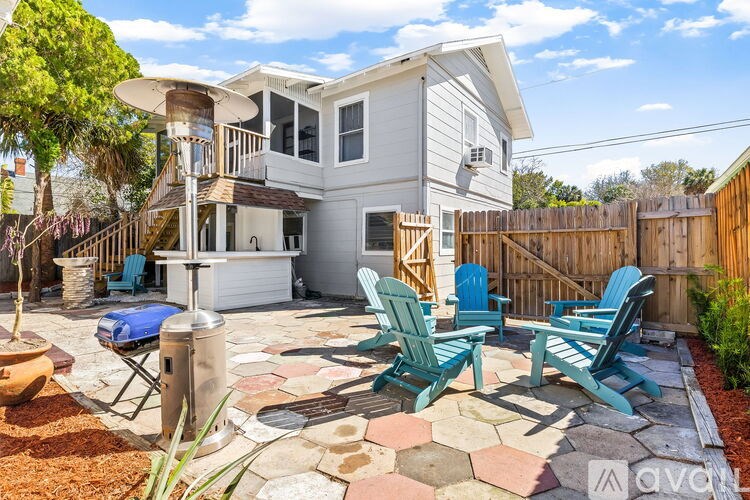 A patio with chairs and a table is in front of a house.