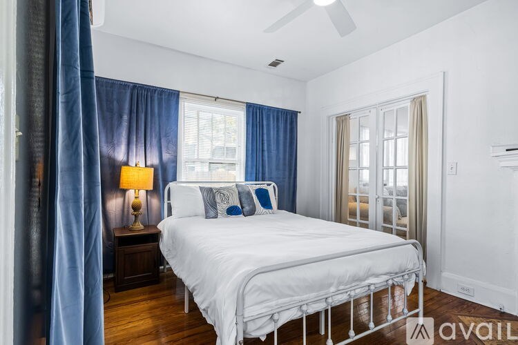A bedroom with a white bed and blue curtains.