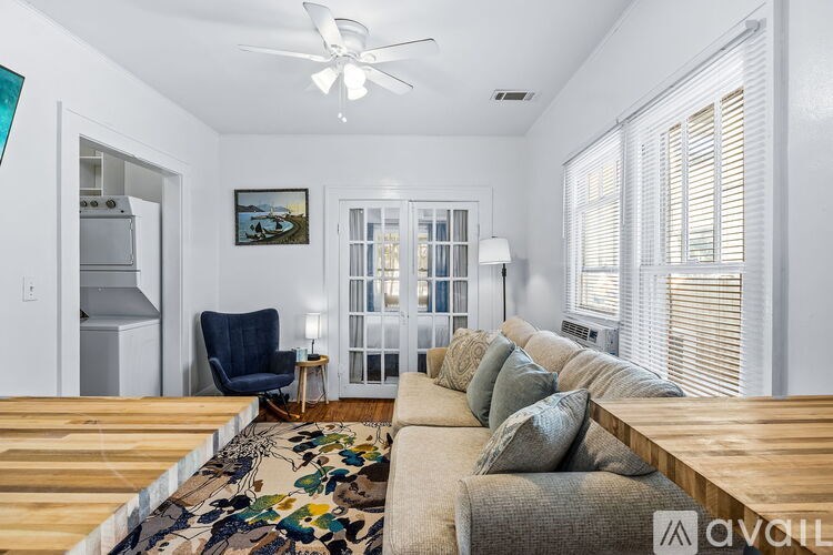 A living room with a couch, a chair, a rug, and a painting on the wall.