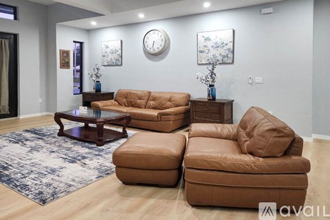 A living room with brown leather furniture and a blue patterned rug.