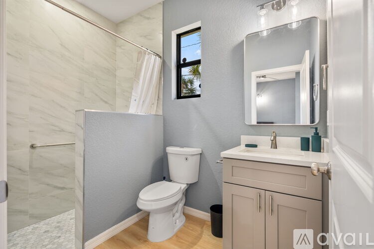 A bathroom with a toilet, sink, and mirror.
