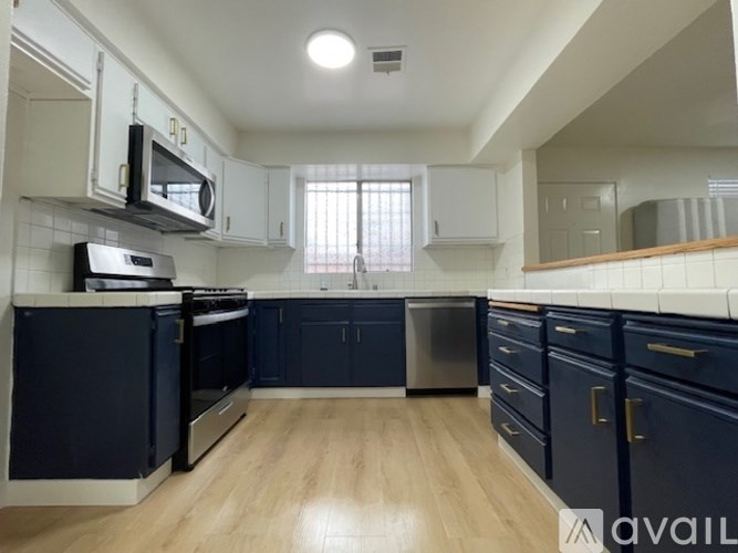 A kitchen with dark blue cabinets and wooden flooring.