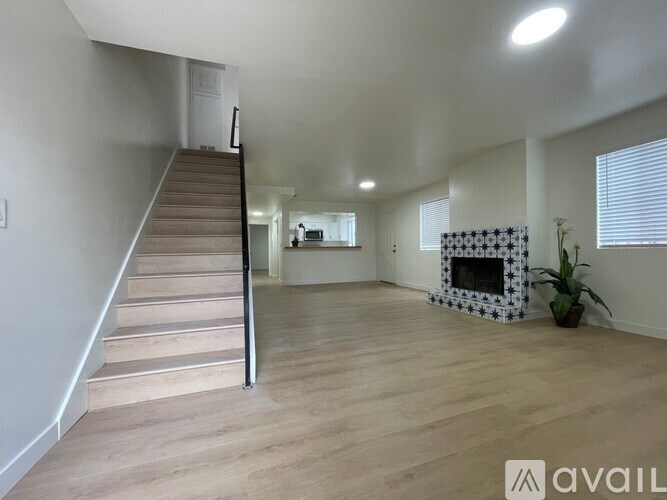 A spacious living room with a fireplace and a staircase.