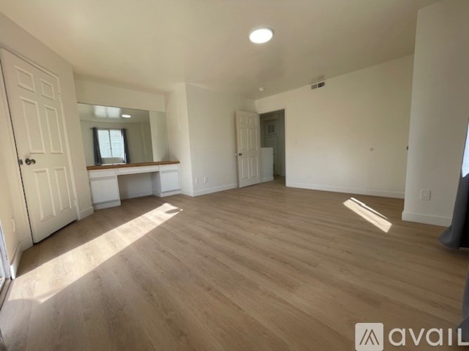 A spacious room with wooden flooring and white walls.