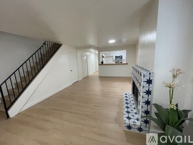 A spacious room with wooden flooring and a staircase with a black railing.