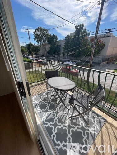 A balcony with a table and chairs overlooking a street.