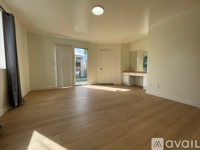 A spacious room with wooden flooring and white walls.