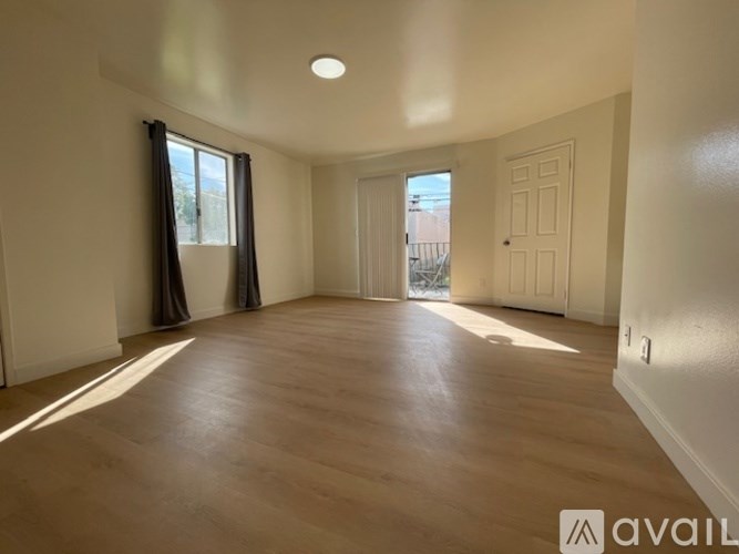 A spacious room with wooden flooring and white walls.