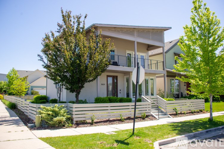 A house with a white fence and a tree in front.
