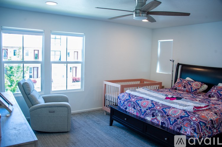 A bedroom with a bed, chair, and a ceiling fan.
