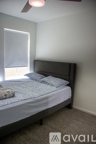A bedroom with a bed, pillows, and a ceiling fan.