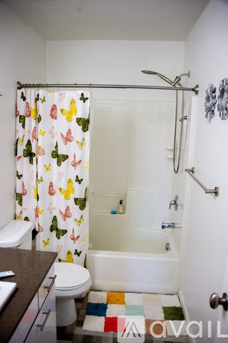 A bathroom with a white tub and a shower curtain with butterflies on it.