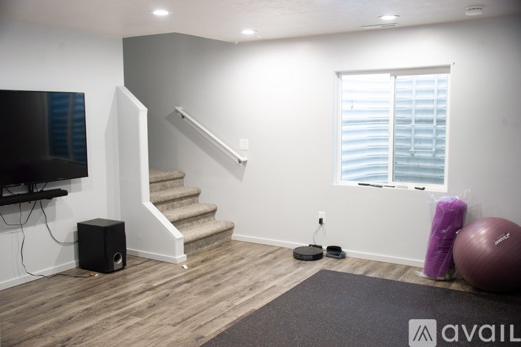 A room with a staircase, a television, and exercise equipment.