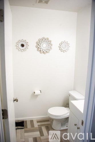 A bathroom with a toilet, a sink and three wall decorations.