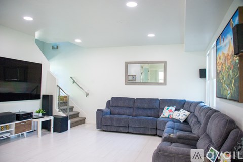 A living room with a grey couch and a staircase.