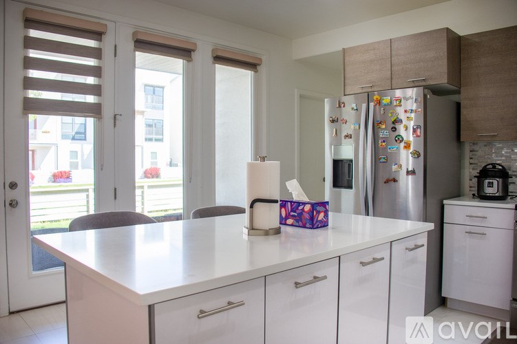 A kitchen with white cabinets and a fridge with magnets on it.