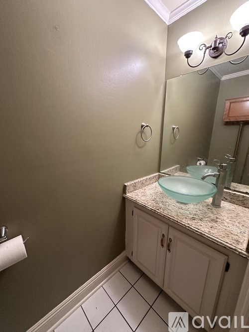 A bathroom with a sink, mirror, and toilet paper roll.