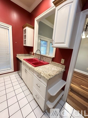 A kitchen with red walls and white cabinets.
