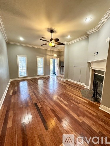 A spacious room with wood flooring and a ceiling fan.