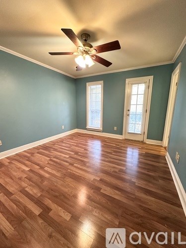 A room with a ceiling fan and wooden flooring.