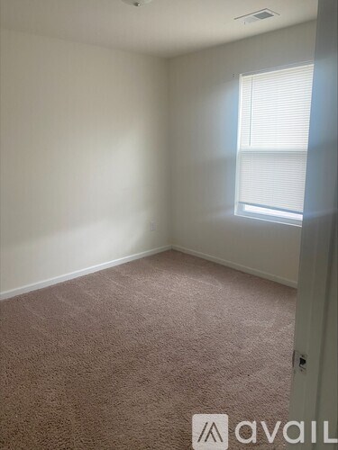 A room with a carpeted floor and a window with blinds.