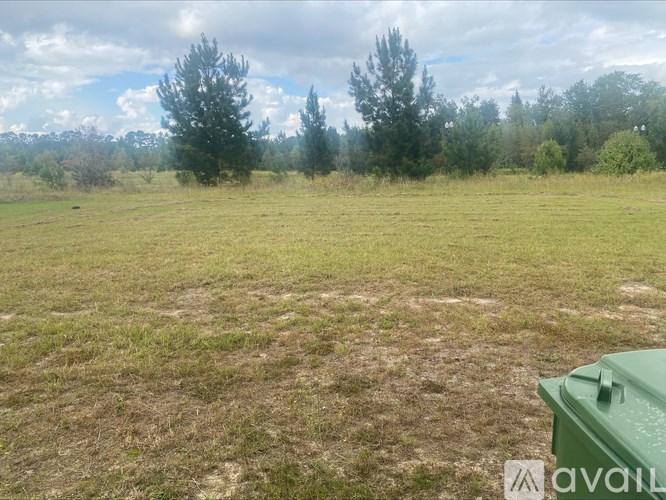 A green container is in the foreground of a grassy field with trees in the background.