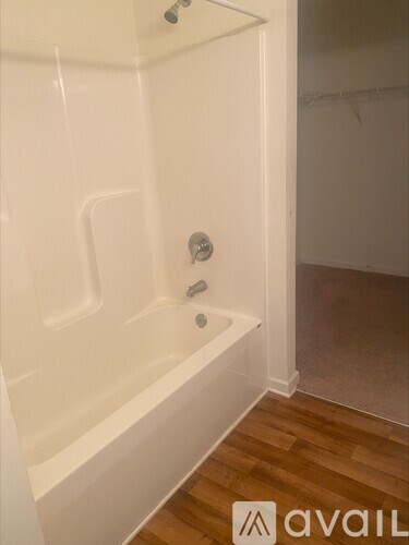 A white bathtub with a shower head and faucet.